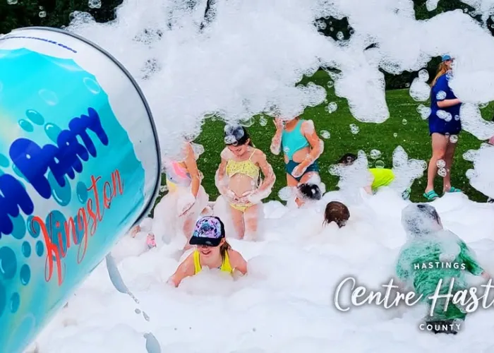 Giant foam cannon shooting foam into air, children playing in the foam